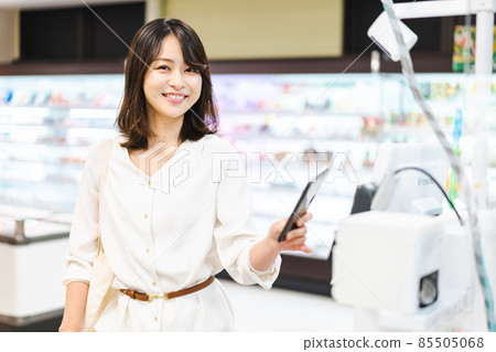 Young woman using smartphone payment at supermarket Young woman using smartphone payment at supermarket 85505068