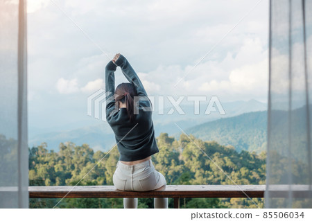 Happy woman relaxing and looking mountain view at countryside home or homestay in the morning. Vacation, blogger, SoloTravel, journey, trip and relaxing concept 85506034