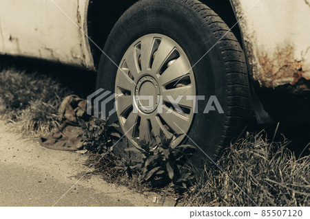Old rusty car wheel. Cracked tires and rusted hubcaps. 85507120