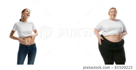 Young smiling slim girl and plus-size woman isolated on white background. Concept of healthy lifestyle, fitness, sport, nutrition and weight loss. Young smiling slim girl and plus-size woman isolated on white background. Concept of healthy lifestyle, fitness, sport, nutrition and weight loss. 85509225
