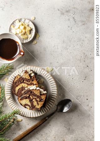 Two slices of zebra cake on a plate, top view, christmas composition with fir branches 85509823