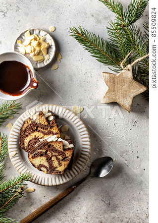 Two slices of zebra cake on a plate, top view, christmas composition with fir branches 85509824