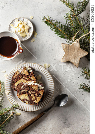 Two slices of zebra cake on a plate, top view, christmas composition with fir branches 85509825