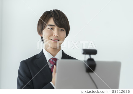 一個年輕人在西裝與網絡攝像頭在線面試在線會議交談的圖像 一個年輕人在西裝與網絡攝像頭在線面試在線會議交談的圖像 85512626