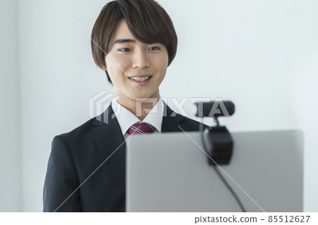 一個年輕人在西裝與網絡攝像頭在線面試在線會議交談的圖像 一個年輕人在西裝與網絡攝像頭在線面試在線會議交談的圖像 85512627