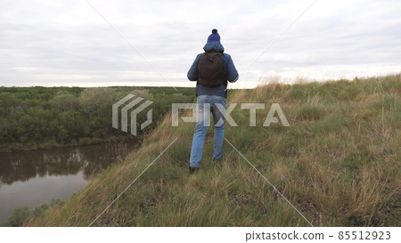 A man travels with a backpack on a mountain by the river. The man is looking for adventure. A weekend on a sports hike alone. Rest at nature. Tourist exploration of the area 85512923