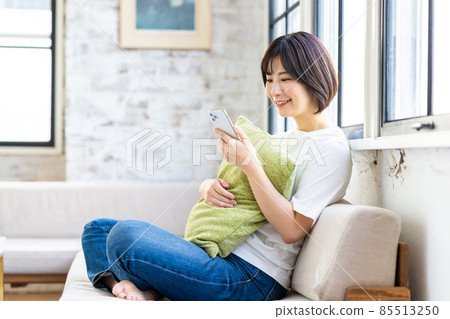 Young woman looking at her smartphone in the living room Young woman looking at her smartphone in the living room 85513250