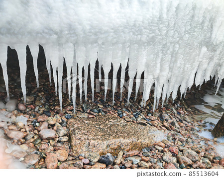 Winter frozen icicles hanging from rock on beach 85513604