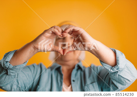 Woman hands making sign heart isolated over yellow color background. Love concept on valentine day 85514230