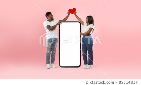 Couple showing white empty smartphone screen holding paper heart 85514817