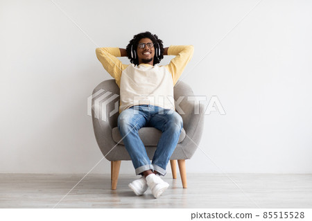 Relax Mode. Young Black Guy Wearing Wireless Headphones Resting In Armchair Relax Mode. Young Black Guy Wearing Wireless Headphones Resting In Armchair 85515528