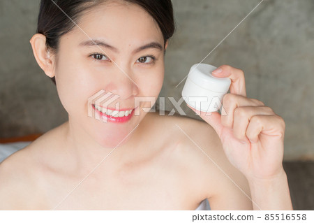 Portrait of young Asian woman holding packaging cream container in her hand. Conceptual of beauty and cosmetic. 85516558