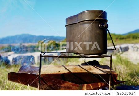Cook rice with a mess tin using a bonfire at the camp Cook rice with a mess tin using a bonfire at the camp 85516634