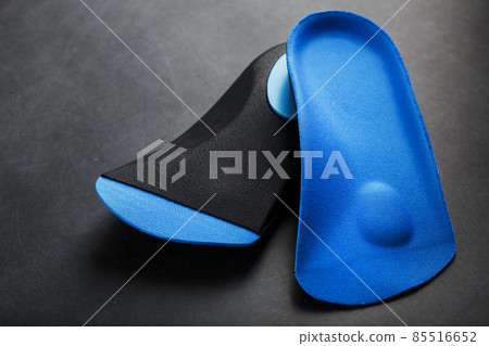 Orthopedic insoles for correction of the blue color of the foot on a black background. 85516652