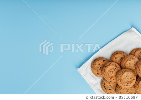 A bunch of oatmeal cookies with chocolate on a napkin on a blue background A bunch of oatmeal cookies with chocolate on a napkin on a blue background 85516687