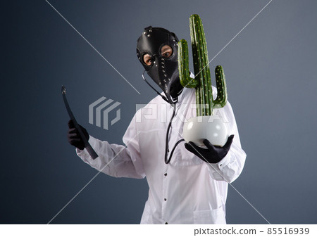 a doctor in a dressing gown, wearing a plague doctor mask with a cactus in his hands 85516939