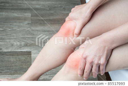 Close up of woman hands holding and massage her knee, suffering from knee pain. Knee pain may be the result of an injury, such as a ruptured ligament or torn cartilage. 85517093