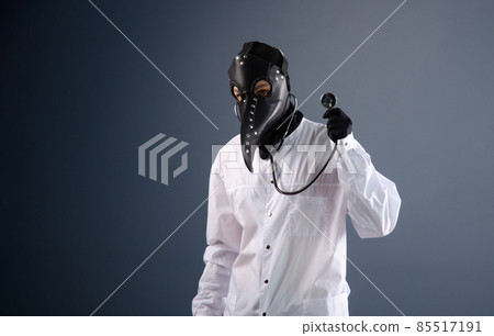 a doctor in a dressing gown wearing a plague doctor mask with a stethoscope in his hands a doctor in a dressing gown wearing a plague doctor mask with a stethoscope in his hands 85517191