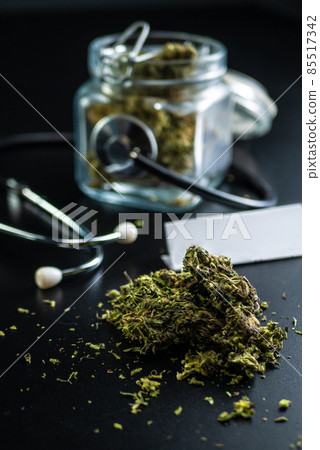 Dry medical cannabis in a jar with a stethoscope on a black background 85517342