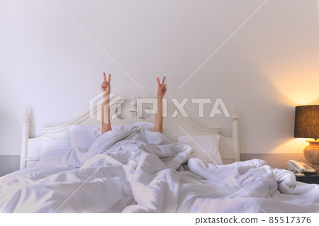 Female in bed showing a victory sign with two hands raised in the air. Female in bed showing a victory sign with two hands raised in the air. 85517376