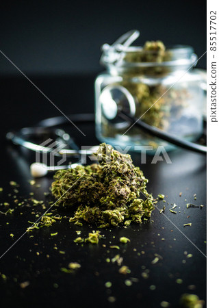 Dry medical cannabis in a jar with a stethoscope on a black background 85517702