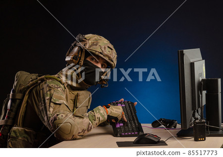 soldier sitting at a computer is conducting a cyber war soldier sitting at a computer is conducting a cyber war 85517773