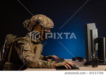 soldier sitting at a computer is conducting a cyber war soldier sitting at a computer is conducting a cyber war 85517780
