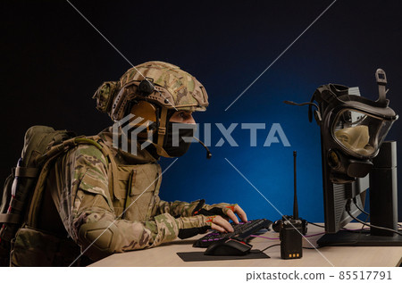 soldier sitting at a computer is conducting a cyber war soldier sitting at a computer is conducting a cyber war 85517791