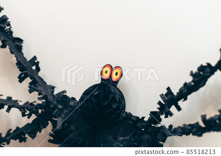 Big yellow eyes of black spider paper decor on white wall. Day of Dead. Halloween decoration. Big yellow eyes of black spider paper decor on white wall. Day of Dead. Halloween decoration. 85518213