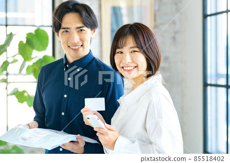 A young couple checking their luggage while looking at their smartphone 85518402
