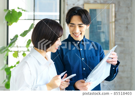 A young couple checking their luggage while looking at their smartphone A young couple checking their luggage while looking at their smartphone 85518403