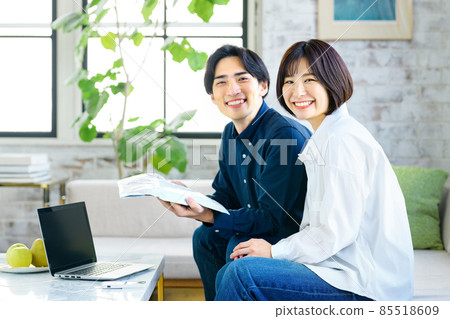 一對年輕夫婦在客廳的電腦前檢查行李 一對年輕夫婦在客廳的電腦前檢查行李 85518609