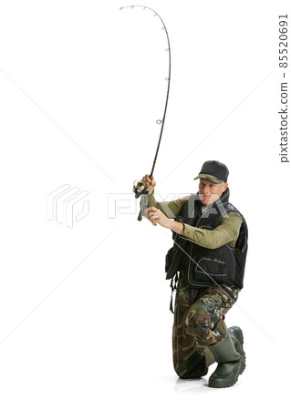 Portrait of young man, professional fisherman with fishing rod, spinning and equipment sitting isolated over white studio background Portrait of young man, professional fisherman with fishing rod, spinning and equipment sitting isolated over white studio background 85520691