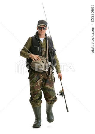 Portrait of young man, professional fisherman with fishing rod, spinning and equipment going to river isolated over white studio background Portrait of young man, professional fisherman with fishing rod, spinning and equipment going to river isolated over white studio background 85520695