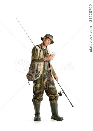 Portrait of young man, professional fishman with fishing rod, spinning and equipment going to river isolated over white studio background Portrait of young man, professional fishman with fishing rod, spinning and equipment going to river isolated over white studio background 85520709