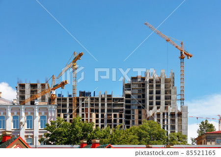 City landscape. Construction of a new multi-storey building using tower cranes and the method of monolithic-frame technology among the old districts of the city. City landscape. Construction of a new multi-storey building using tower cranes and the method of monolithic-frame technology among the old districts of the city. 85521165