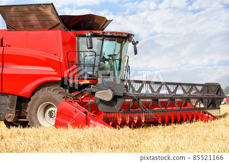 Fragment of a standing red large combine harvester for harvesting wheat on a summer day. 85521166