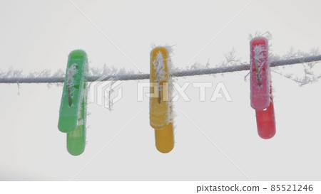 Multicolored clothespins on a rope in hoarfrost hang on a rope in the winter outside in the snow 85521246