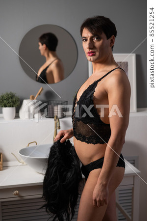 Homosexual preening in front of the mirror. A transgender man combing a wig. Homosexual preening in front of the mirror. A transgender man combing a wig. 85521254