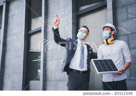 Working in the newnormal, the project engineer and the team leader wear masks. and consulting on the building's solar cell system.engineers team discuss the use of solar energy in modern buildings. Working in the newnormal, the project engineer and the team leader wear masks. and consulting on the building's solar cell system.engineers team discuss the use of solar energy in modern buildings. 85521595