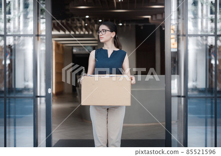 portrait of a female company employee standing outdoor with box of stuff. Leaving business. Female office worker lost her job.Job loss due to COVID-19 virus pandemic concept 85521596
