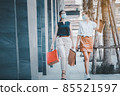 social distancing new normal concept.portrait of two happy girls walking together wearing medical face masks, walking outdoors in the evening near mall after covid epidemic , holding shopping bags. 85521597
