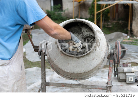 Labore worker operating concrete cement mixer at construction site. Labore worker operating concrete cement mixer at construction site. 85521739