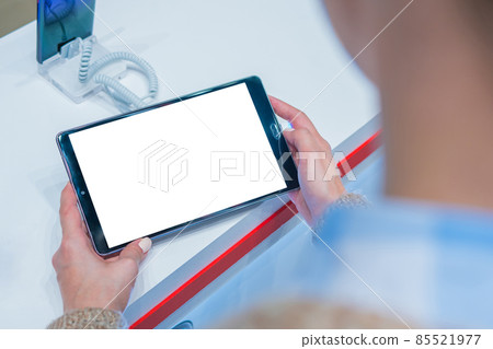 Mock up: woman looking at tablet with blank white screen at store, shop 85521977