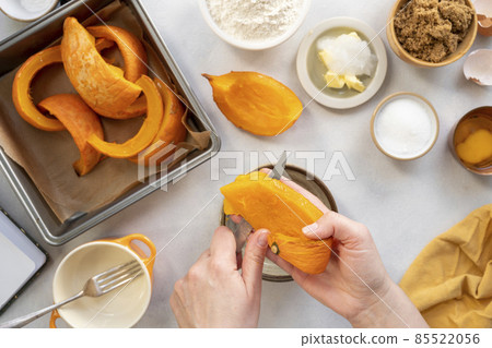 Process of peeling, cutting orange pumpkin by female hands. Cooking pumpkin cake or muffins. Top view. Step by step process. 85522056