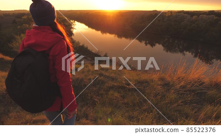 The girl goes down from a high mountain at the sunrise raising her hands up. Woman traveler goes down to the river. Achieve your goals in your life path. The lifestyle of a tourist in an active The girl goes down from a high mountain at the sunrise raising her hands up. Woman traveler goes down to the river. Achieve your goals in your life path. The lifestyle of a tourist in an active 85522376