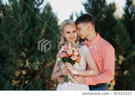 Bride and groom at wedding Day walking Outdoors on spring nature. Bridal couple, Happy Newlywed woman and man embracing in green park. Loving wedding couple outdoor. Wedding shot of bride and groom in 85522521