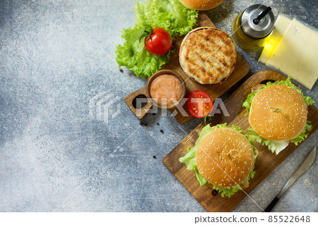 Delicious grilled burgers, hamburger sandwich with cutlet of chicken meat, melted cheese, tomatoes and bacon on a wooden board. Top view flat lay. Free space for your text. Delicious grilled burgers, hamburger sandwich with cutlet of chicken meat, melted cheese, tomatoes and bacon on a wooden board. Top view flat lay. Free space for your text. 85522648