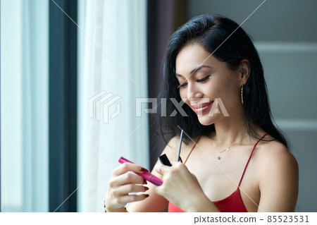 Beautiful young woman doing evening make-up next to the window 85523531