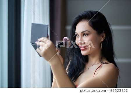 Beautiful young woman doing evening make-up next to the window 85523532